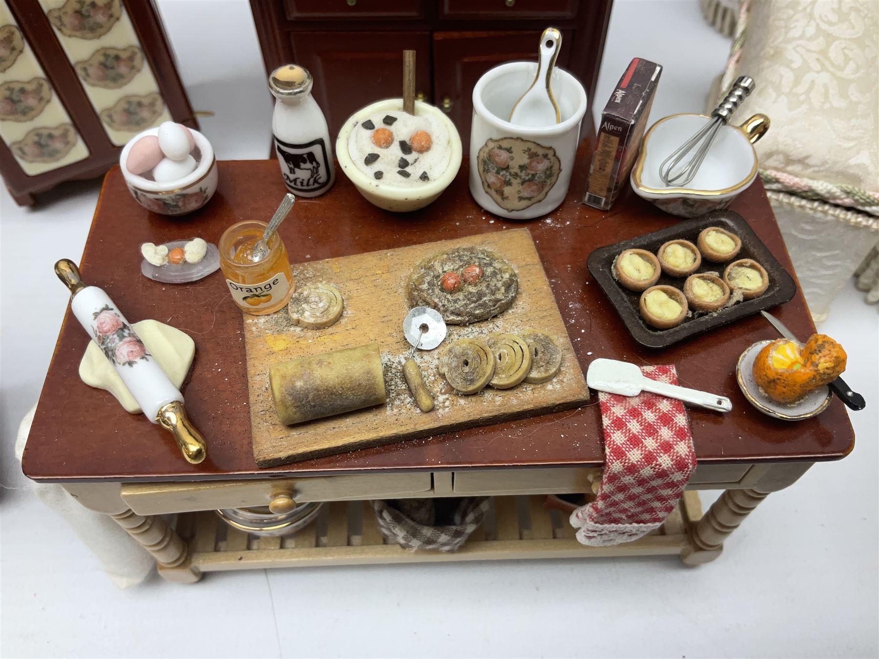 Collection of kitchen and bedroom dolls house furniture, to include two units housing Reutter, Germany ceramic plates, tea wares and accessors comprising one example with a Belfast sink with various pots and pans and jars, the second housing various baking equipment, two dressers, baking table, shelf unit housing various jars of herbs and basket of produce, fridge, and lace and jacquard bedroom suite including bed, pair of bedside tables, dressing table and ottoman