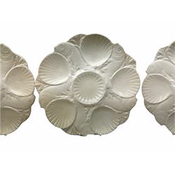 Set of six Minton white glazed oyster dishes, modelled as alternating scallop shells and fish, with printed marks beneath, D26.5cm.