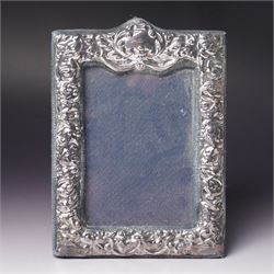 Embossed silver photograph frame London 1985 aperture 12.5cm x 8.5cm, another with scroll top Birmingham 1921 13cm x 9cm and a circular frame Birmingham 1909 6cm
