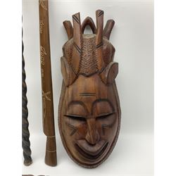 Carved wooden tribal mask, together with a carved wooden walking stick with loop handle and elephant and lion mask decoration, wooden souvenir dagger and similar sword and a carved wooden crocodile shoe horn 