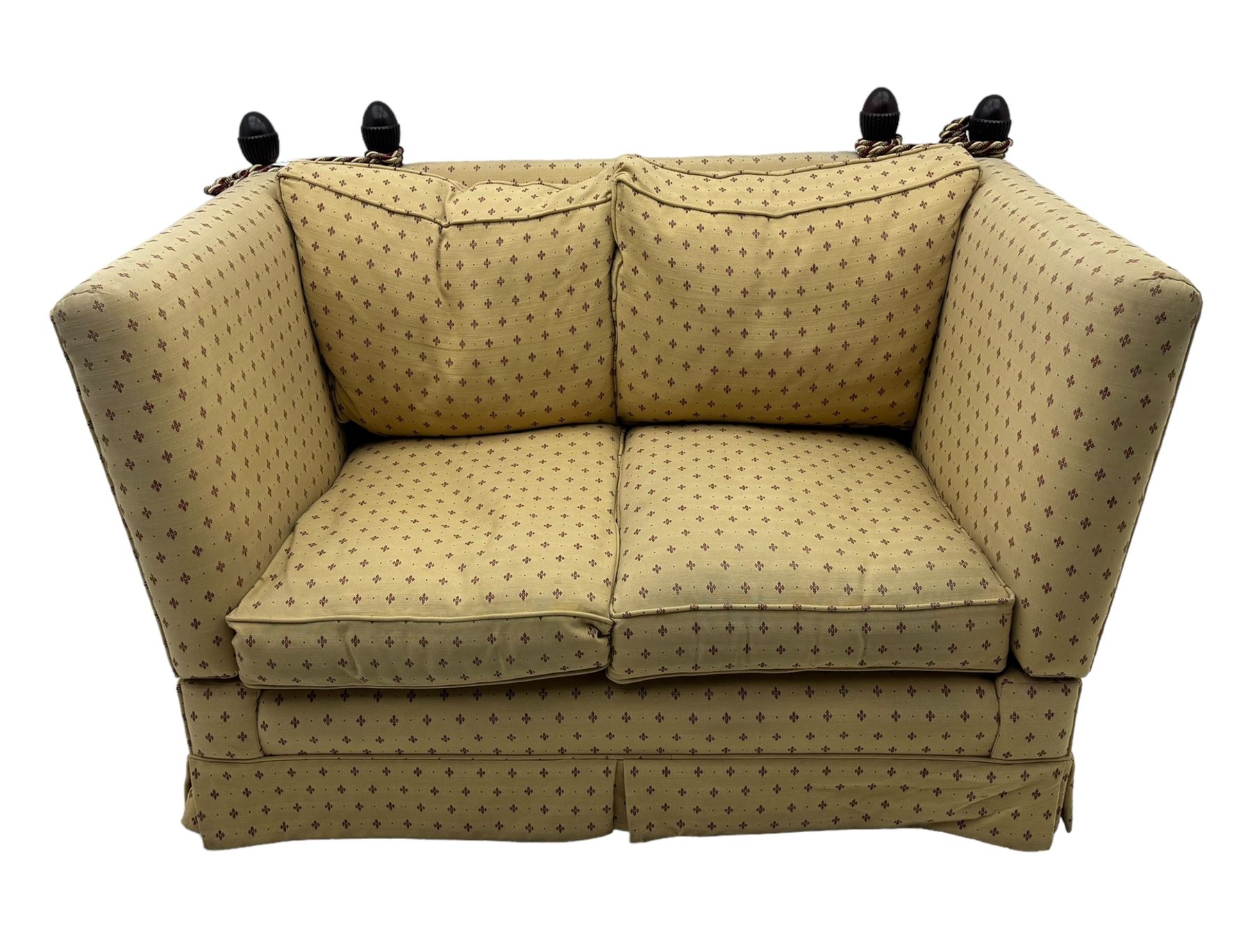 20th century Knole design two seat sofa, high back and double drop-arm joined by mahogany finials and ties, upholstered in camel ground fabric with red lozenge design, on turned supports with brass castors