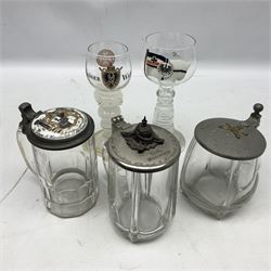 Three German clear glass steins - one with pewter lid inscribed as a leaving present to a comrade in an Artillery/Grenade regiment; one applied with crossed rifles and a pickelhaube to the lid with Christmas 1914 inscription; the other with inset porcelain plaque decorated with a crest and inscription; and two hock glasses - one enamelled with the German Empire Imperial Navy War Ensign (5)