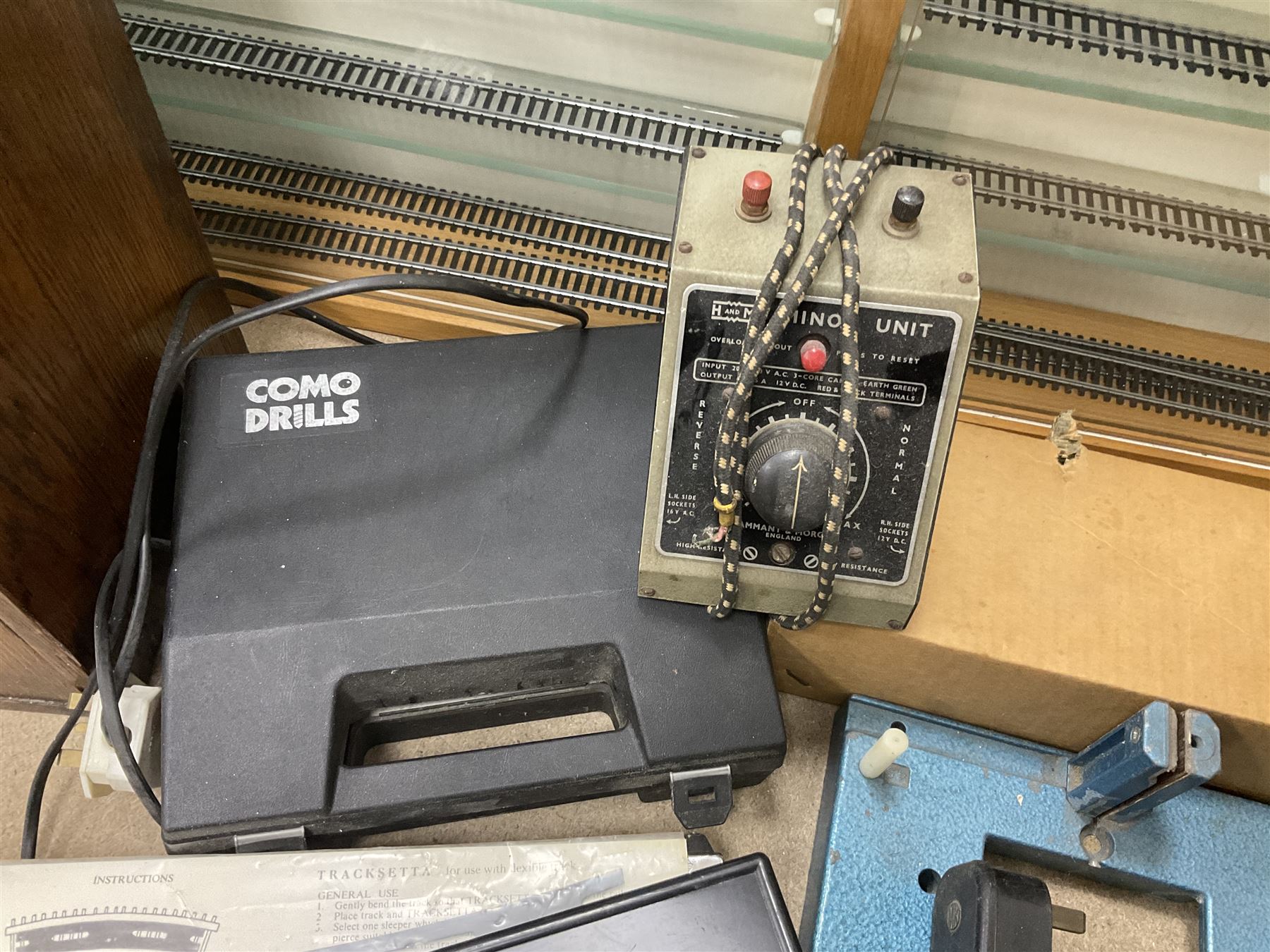 Six shelved cabinets for displaying ‘00’ gauge locomotives comprising plain plywood and white painted examples with track applied to various shelves, largest H63cm, W107cm, D27cm; Collection of tools for building model locomotives to include Weller PU-2D Soldering Pencil and Standard Tip Soldering Iron 20W/230V, Humbrol Modellers Airbrush, Power Supply Units and two wooden chests one of which housing a collection of tools including tweezers, scalping tools, wrenches etc 