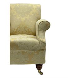 Traditionally shaped hardwood-framed armchair, rolled back and arms, upholstered in pale gold and cream damask fabric with repeating foliate pattern, on turned feet with brass cups and castors