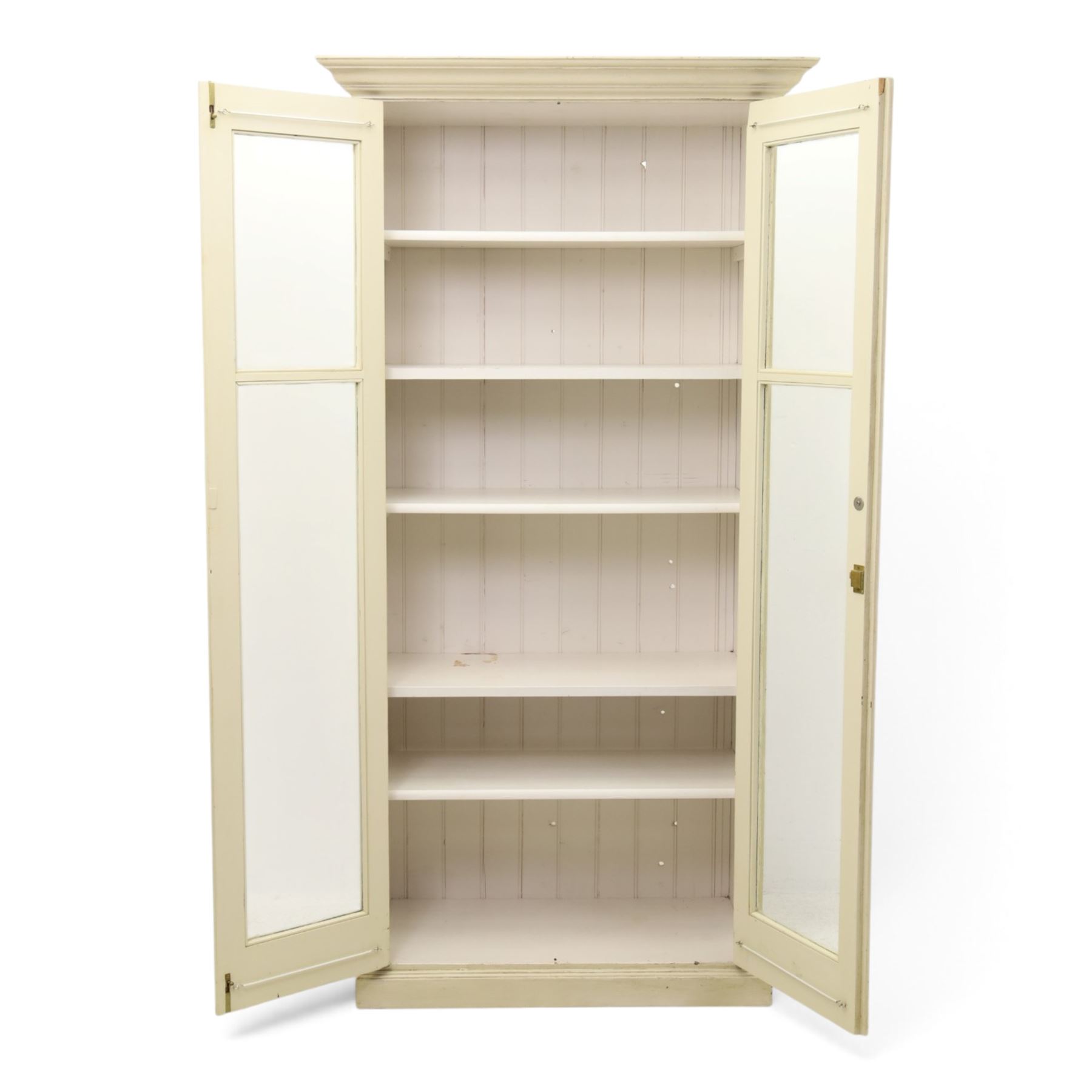 Traditional white painted pine display cabinet, projecting cornice above two glazed doors enclosing five fixed shelves, tongue and groove back raised on a plinth base