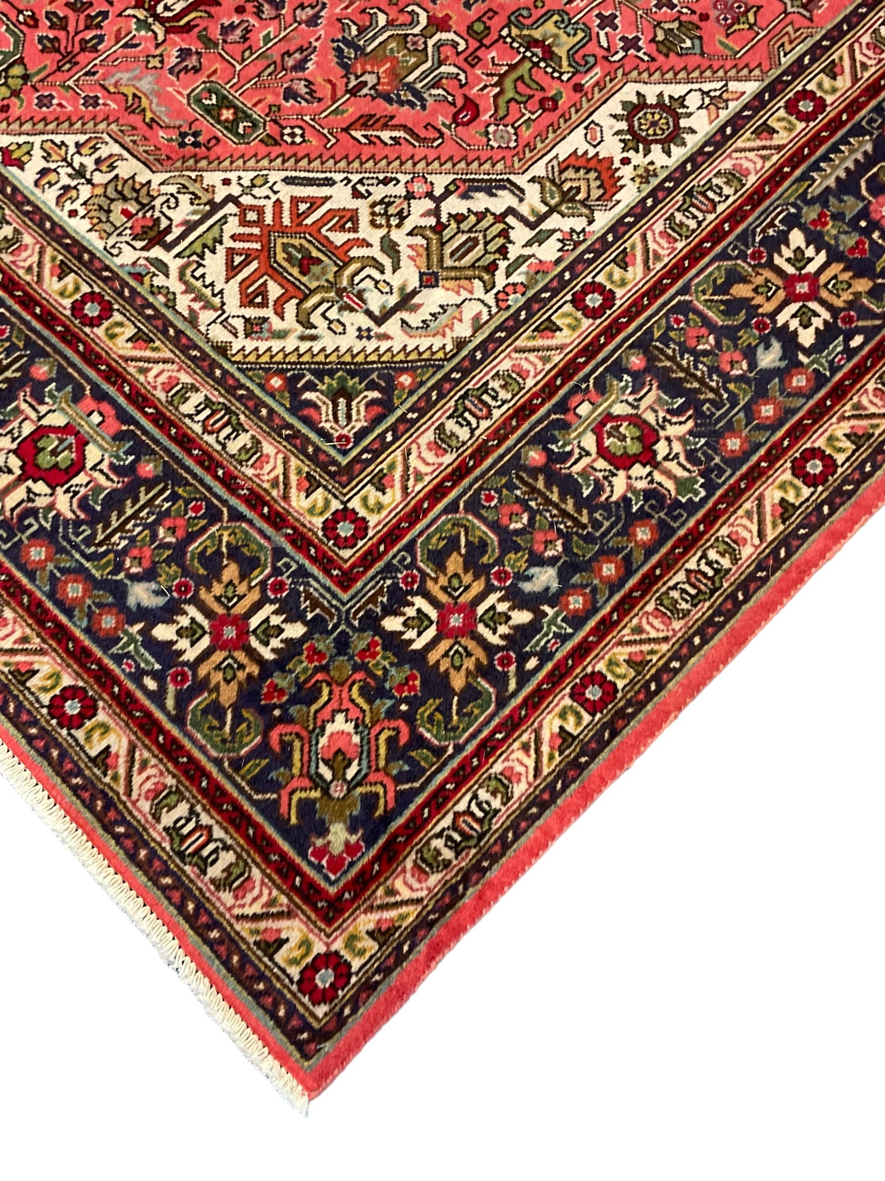 North West Persian pink ground Tabriz carpet, central indigo ground medallion surrounded by stylised plant motifs and trailing foliage, the main border with overall floral design within guard stripes 