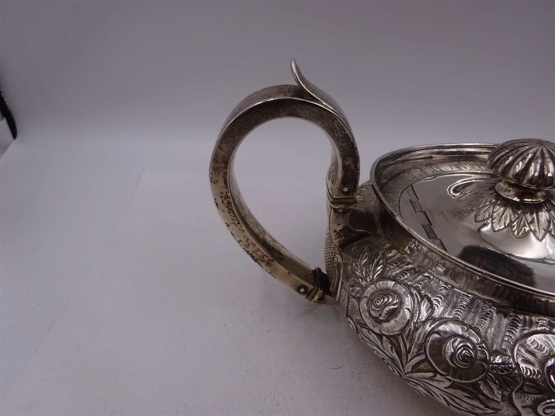 George III Irish silver teapot, of squat circular form, the body with repousse and chased floral and C scroll decoration, with capped C handle and ivory insulators, engraved to base 'Presented to Troop Sergeant Major John Percival, of the 4th Dragoon Guards by Alex D. Tait, Esq, late Captain in that corps as a mark of approbation of his steady and upright conduct when Sergeant Major of his Troop, Dublin, June 2nd 1843', hallmarked William Law, Dublin 1817, H12.5cm, This item has been registered for sale under Section 10 of the APHA Ivory Act