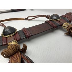 Mandingo sword with 63cm plain curving steel blade and leather covered grip with white metal ribbed spherical pommel; in decorative leather leaf scabbard with plaited tassels and shoulder strap L78cm overall