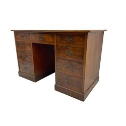 Late 19th to early 20th century walnut pedestal desk, rectangular top inset with red tooled leather writing surface, over a central frieze drawer flanked by two pedestals, each fitted with four graduated drawers with brass escutcheons and drop handles, the whole raised on a plinth base