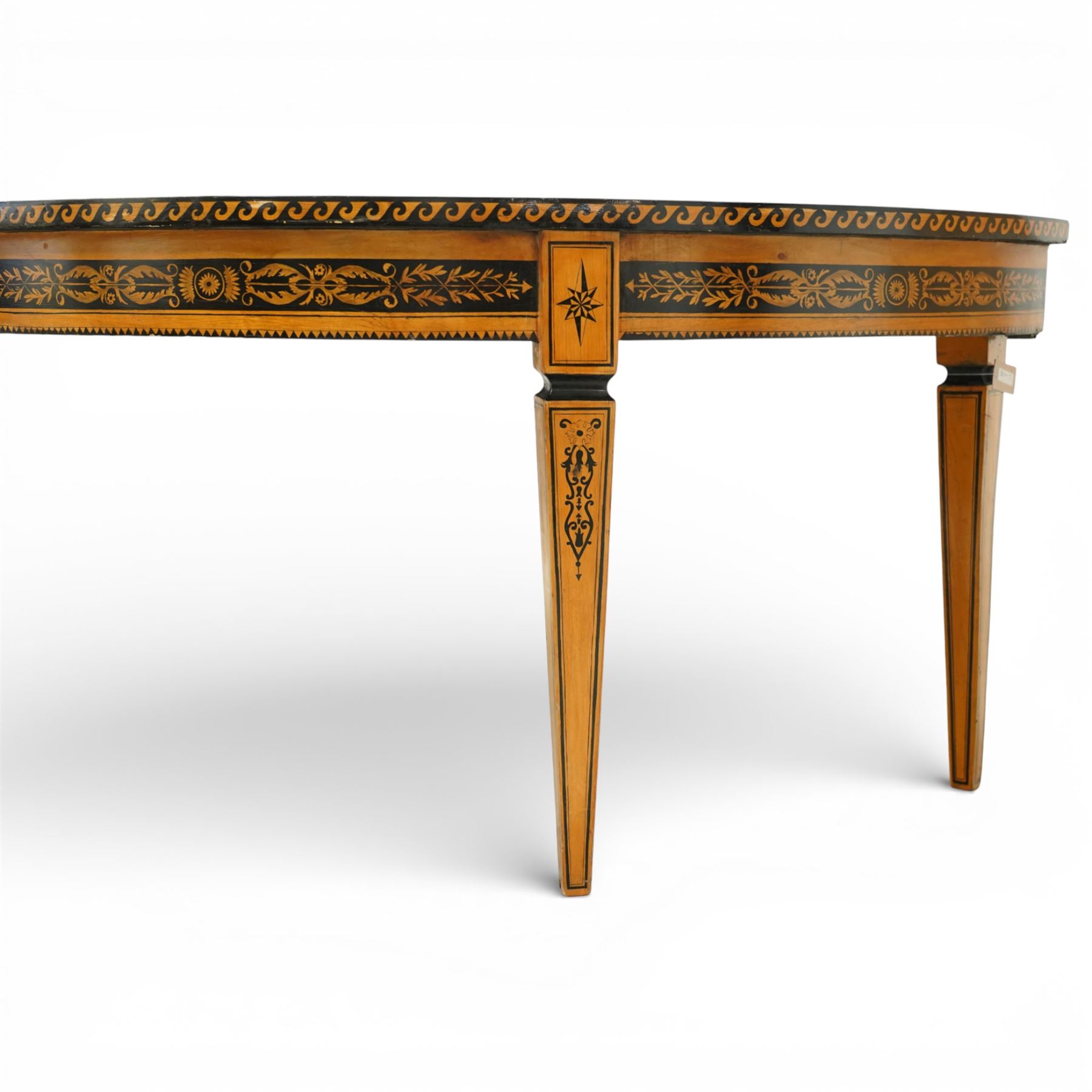 20th-Century Louis XVI-Style satinwood and penwork circular table or pair of console tables, the circular quarter-veneered top decorated in penwork with a central classical mask head motif within scrolling foliate and anthemion ornament on a contrasting black ground, above a conforming frieze decorated with Greek key-type scrolls. Raised on square tapering legs, each with an upper block panel decorated with compass-star motifs.