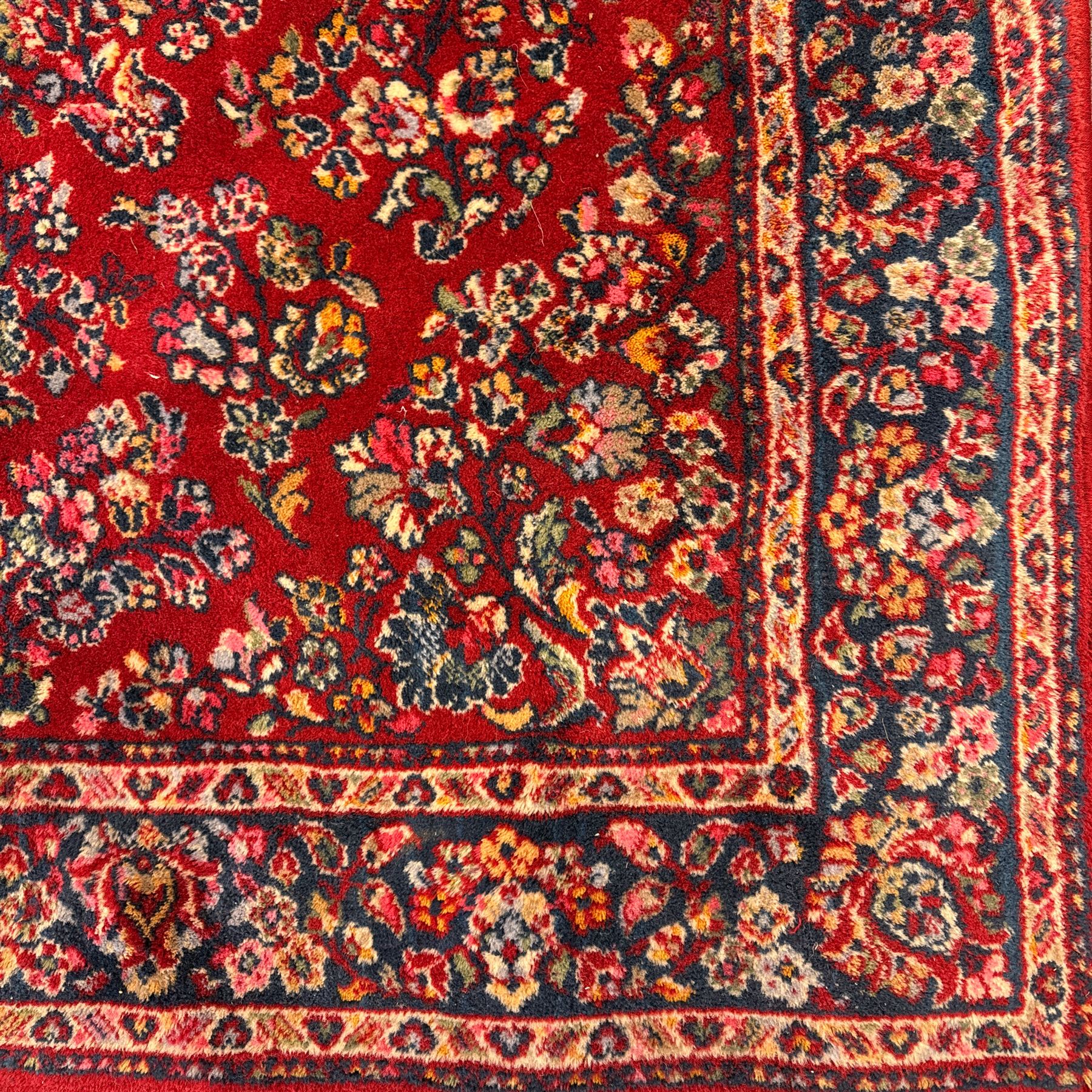 Persian Isfahan-style hand-knotted rug, crimson ground, with an intricated all-over floral spray design with palmettes and leaves, wide midnight blue main border with rosette and palmette motif, flanked by narrow guard borders  