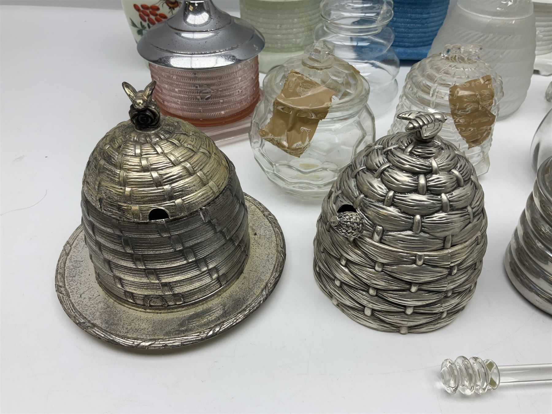 Collection of glass beehive honey pots, to include a blue slag example, milk glass, pink, green, etc together with four white metal examples (16) 