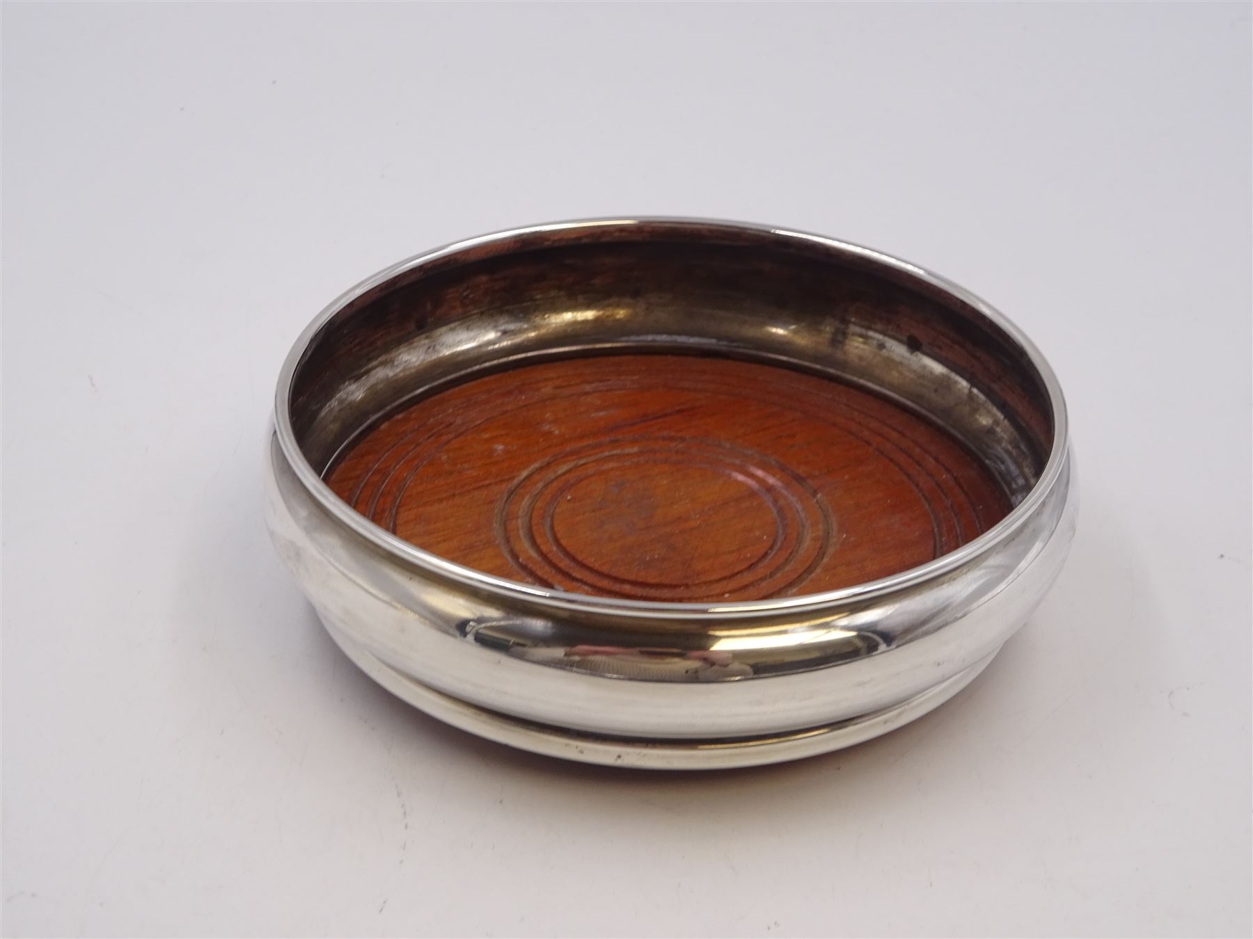 Modern silver mounted bottle coaster, of plain circular form with turned mahogany centre, hallmarked W I Broadway & Co, Birmingham 1979, D13cm