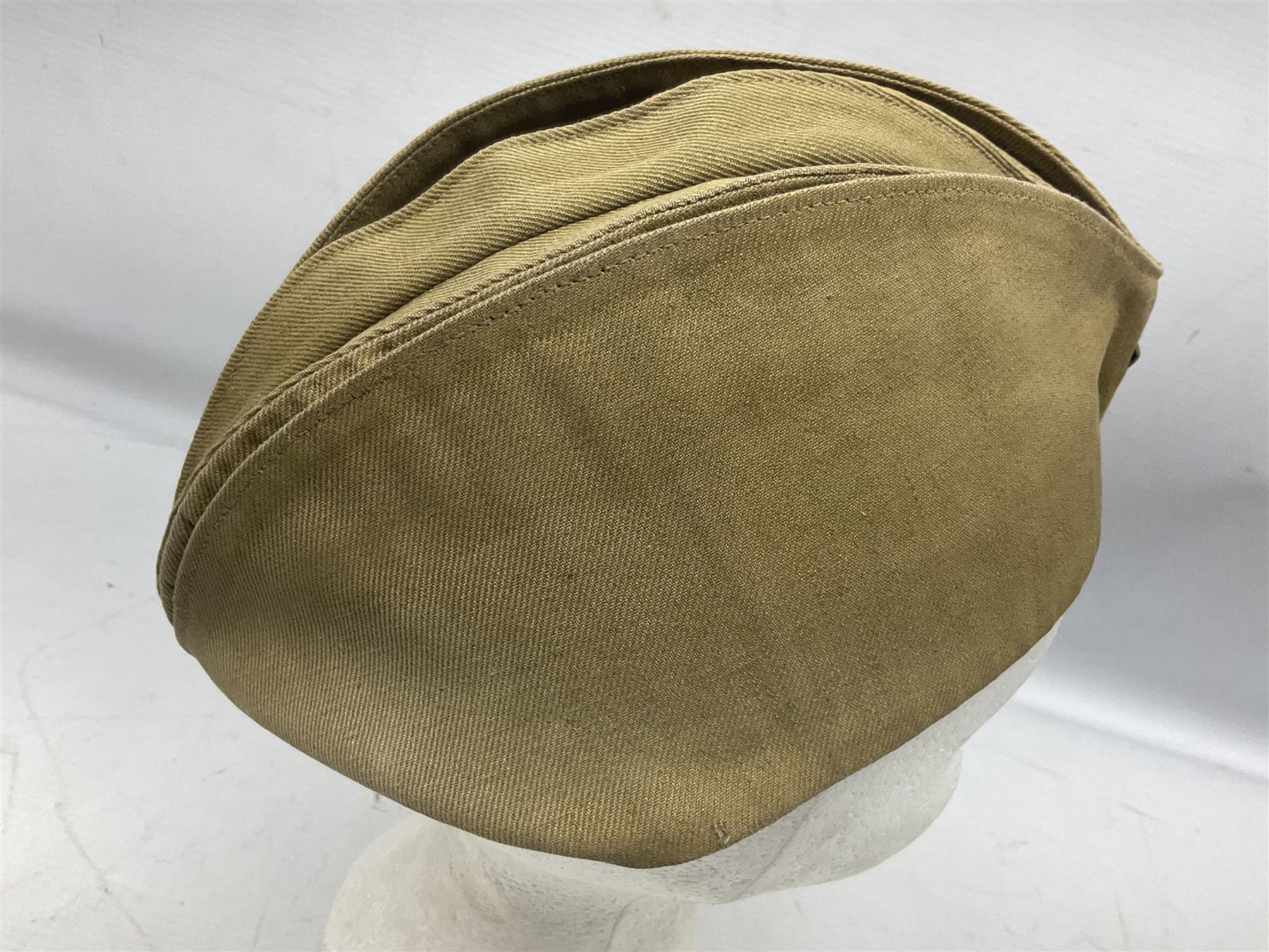 Four side caps - WW2 Russian, post-WW2 Russian and two East German; all with badges, one with multiple metal badges (4)
