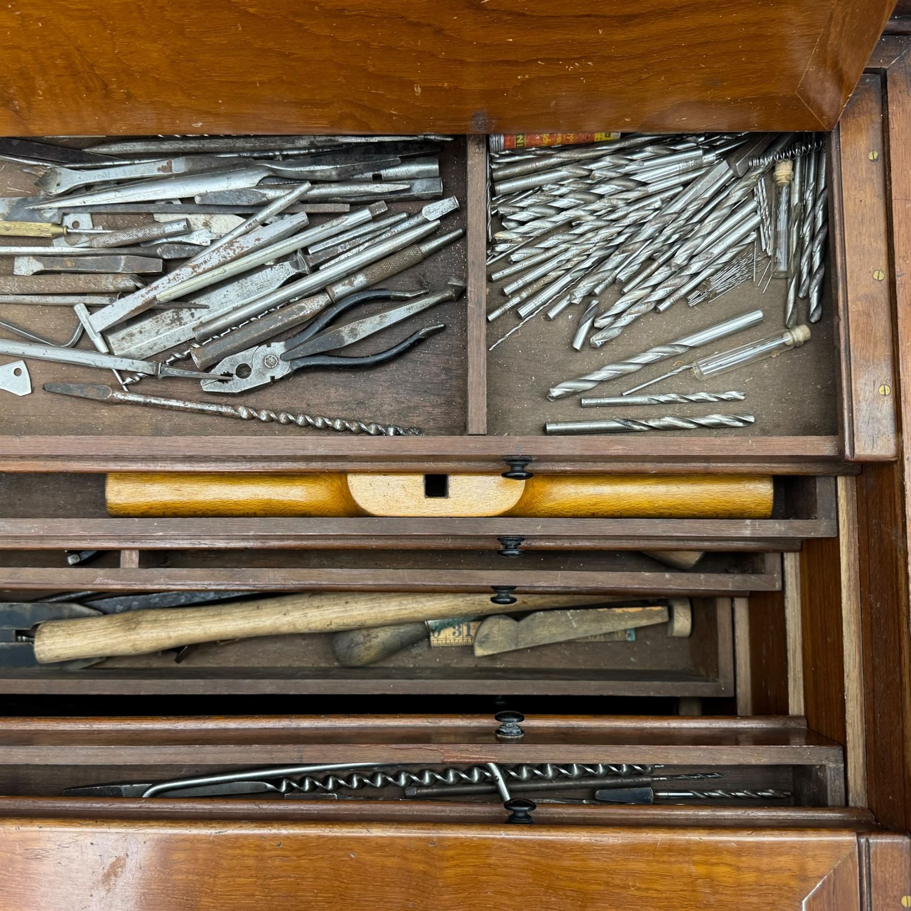 20th century black painted camphorwood lined tool chest, rectangular hinged lid over moulded edge, black painted exterior with iron straps and carry handles, the interior fitted with sliding lidded trays and drawers with turned handles, containing an assortment of hand tools