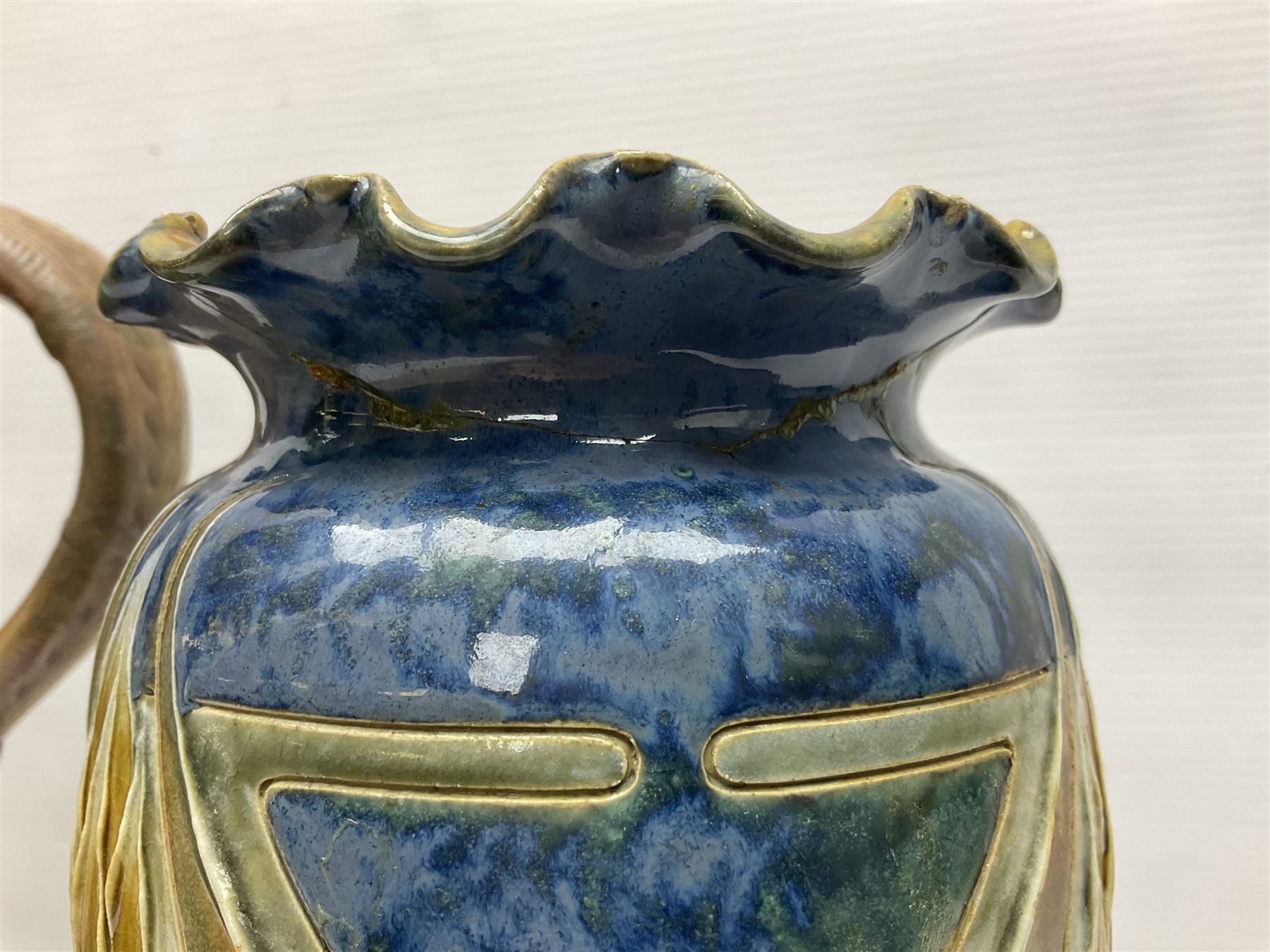 Early 20th century Royal Doulton stoneware vase, decorated with a stylized floral design below a wavy rim, monogrammed B.N, possibly for Bessie Newbery, H28cm, together with an early 20th century glazed jug, heavily carved throughout (2)