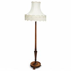 20th century walnut standard lamp, flared and faceted column over circular stepped base with shaped feet, with later scalloped cream fabric shade and fringe trim