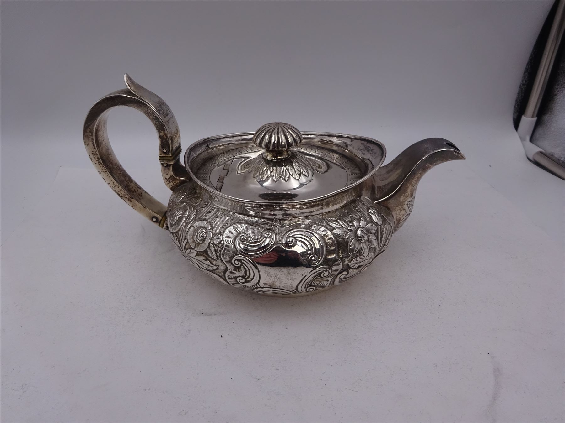 George III Irish silver teapot, of squat circular form, the body with repousse and chased floral and C scroll decoration, with capped C handle and ivory insulators, engraved to base 'Presented to Troop Sergeant Major John Percival, of the 4th Dragoon Guards by Alex D. Tait, Esq, late Captain in that corps as a mark of approbation of his steady and upright conduct when Sergeant Major of his Troop, Dublin, June 2nd 1843', hallmarked William Law, Dublin 1817, H12.5cm, This item has been registered for sale under Section 10 of the APHA Ivory Act