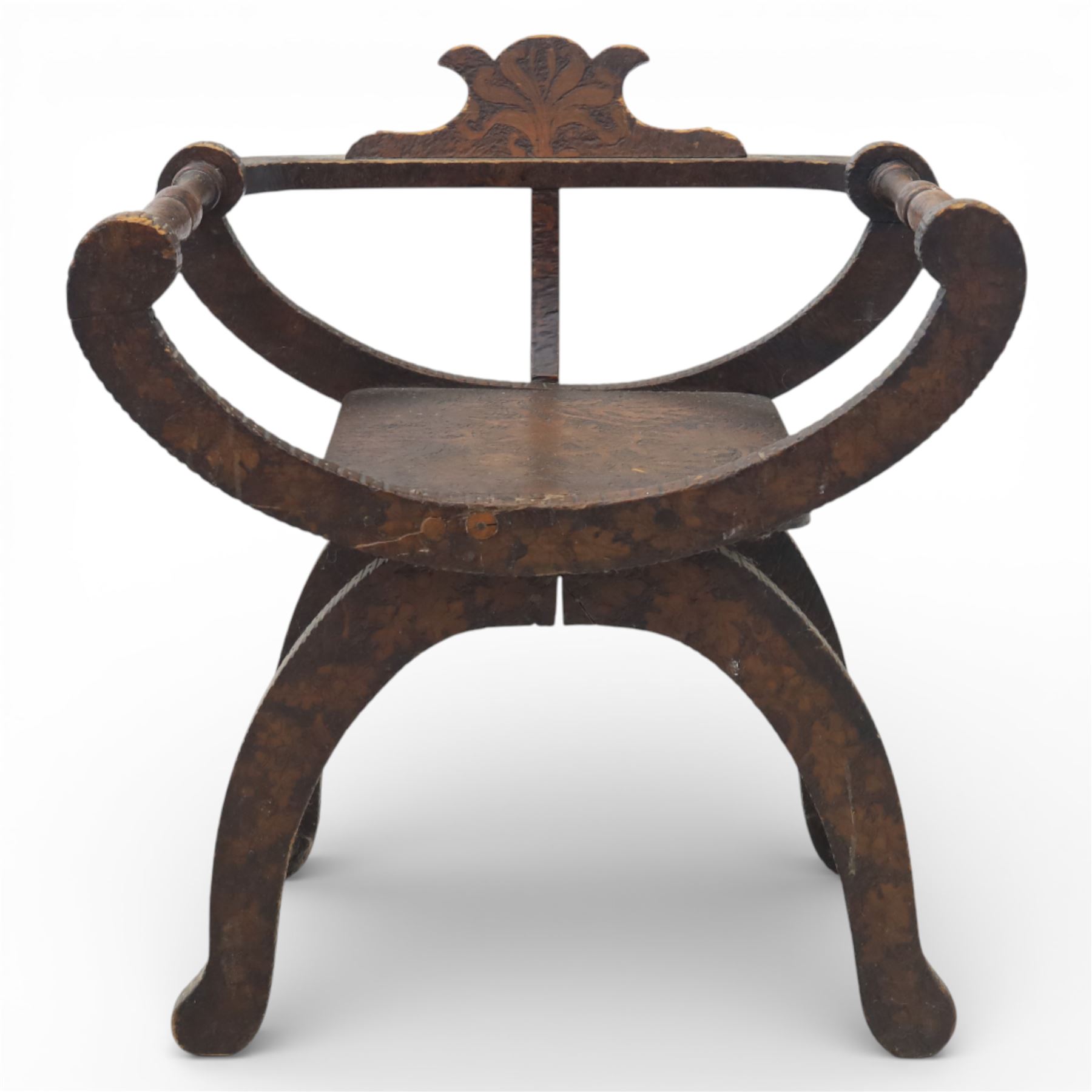 Late 19th century Savonarola style oak chair, X-frame construction with carved and shaped cresting rail, the curved arms with chip carved decoration, turned horizontal supports, solid dished seat with adzed surface, raised on shaped splayed feet
