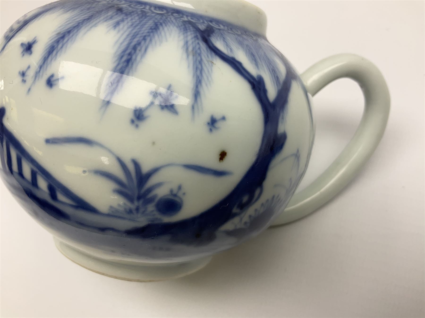 Two late 18th/early 19th century Chinese export teapots, the largest example of globular form with curved handle and straight spout, decorated in the Mandarin style with figural scenes surrounded by red scale reserves, H13.5cm, the second smaller example decorated in underglaze blue with two musicians in a landscape set with willow tree and fence, H10.5cm

