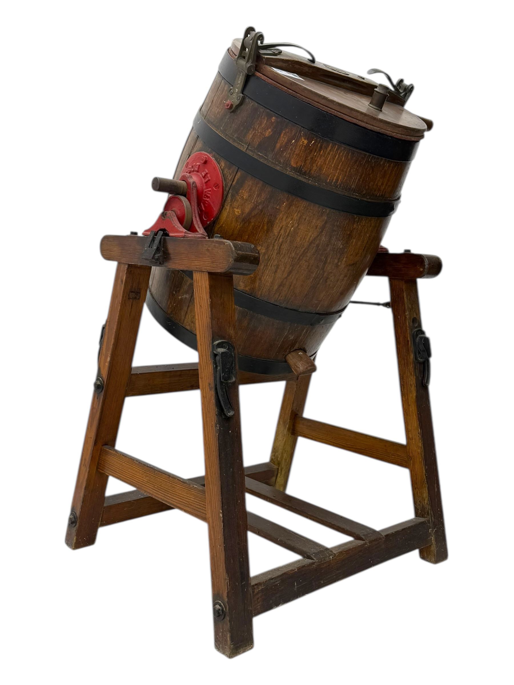 19th century oak and cast iron rotary butter churn, with coopered barrel body, domed lid with filler opening and cast iron securing arms, on tilting iron-mounted frame with crank handle and support rails