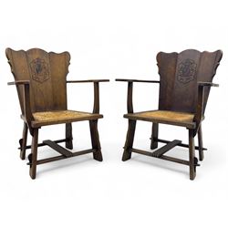 Pair of Arts and Crafts oak armchairs each with shaped backrest centred by polychrome pain...