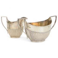 Early 20th century four piece silver tea service, comprising teapot, hot water pot, open sucrier and milk jug, all of oval part fluted form, the teapot and hot water pot with Bakelite type handles and finials, hallmarked James Deakin & Sons (John & William F Deakin), Sheffield 1918