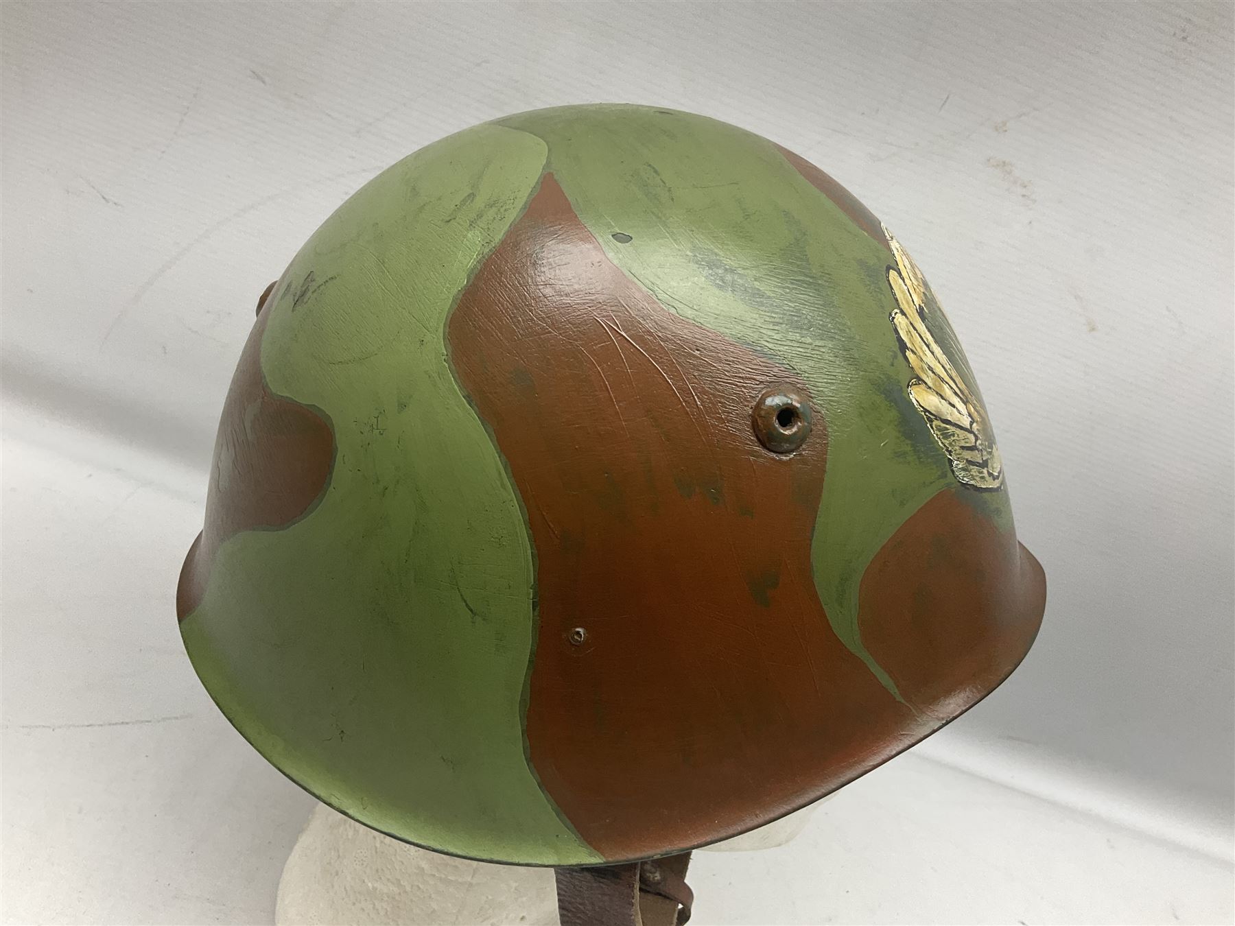 1960s Italian parachutist helmet with liner; camouflage paintwork with parachutist crest to the front