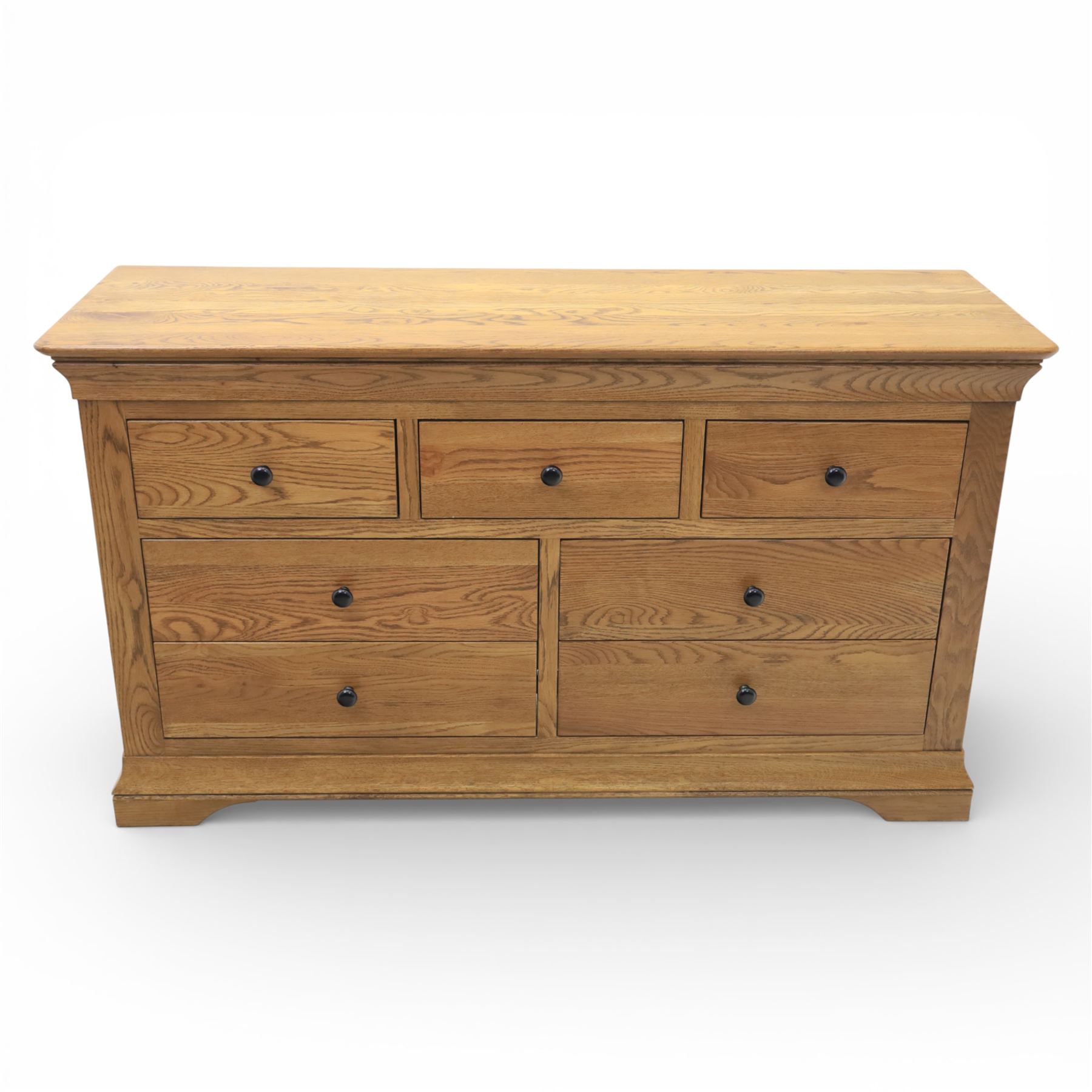 Contemporary oak veneered sideboard, moulded rectangular top above a six drawer arrangement, three over three, each drawer with turned ebonised style knob handle, panelled ends, raised on a shaped plinth base with bracket feet