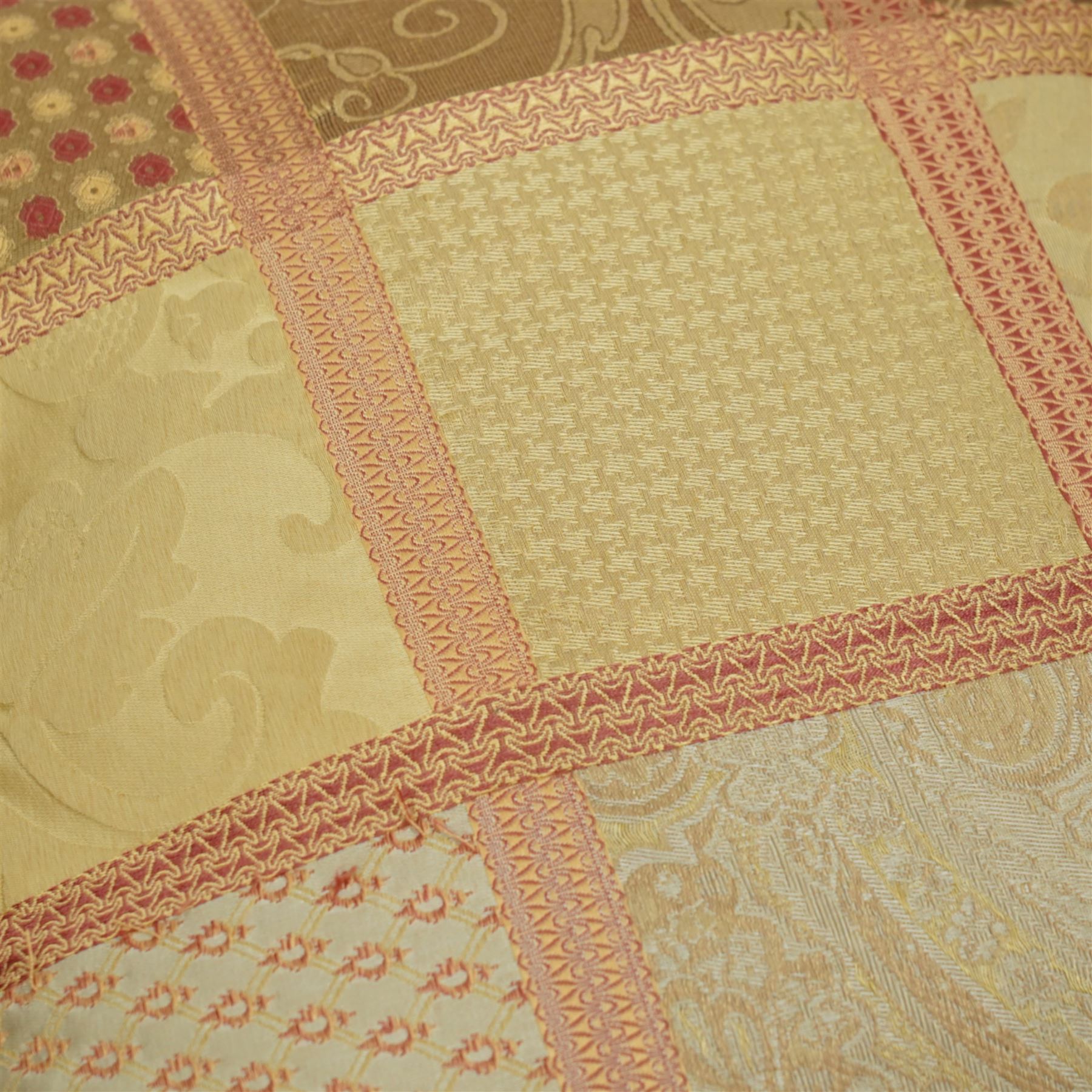 Contemporary set of six jacquard woven scatter cushions, each with a patchwork effect of floral, damask and dotted motifs in a palette of gold, blush, and cream, piped edging throughout, together with a square cushion with embroidered tree and bird design on a cream linen ground (H 40cm, W 40cm, D 14cm)