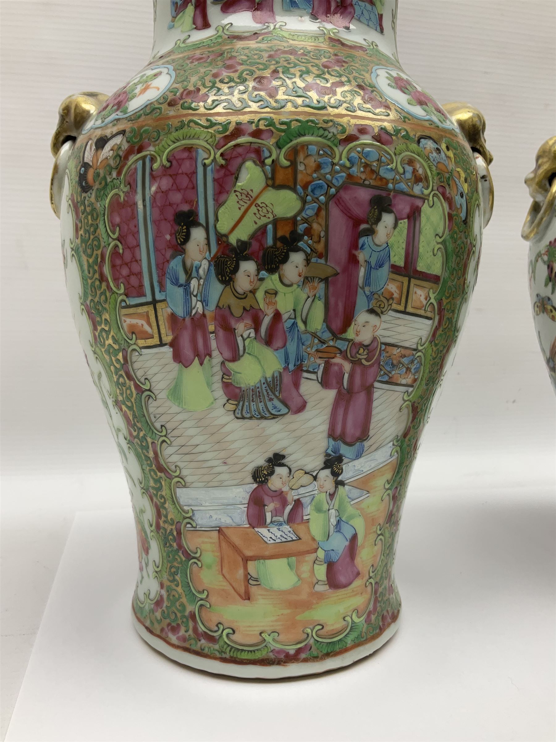 Pair of 19th century Chinese Famille Rose vases and covers, each of baluster form with twin gilt lion mask ring handles to shoulders, the flattened domed covers with gilt temple lion finials, each decorated with alternating reserves of bijin and attendants, and birds and butterflies amongst blossoming peonies, against a gilt ground profusely decorated with stylised scrolls, H32.5cm