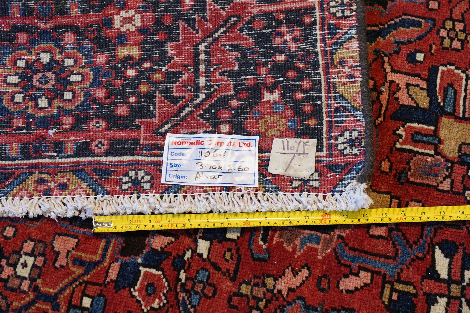 North West Persian Heriz/Ahar hand-knotted carpet, brick red field with a central bold stepped star medallion with pendants, surrounded by angular floral and geometric motifs, ivory spandrels, enclosed by a dark indigo border of stylized rosettes and vine motifs with multiple guard stripes, cotton fringe ends 