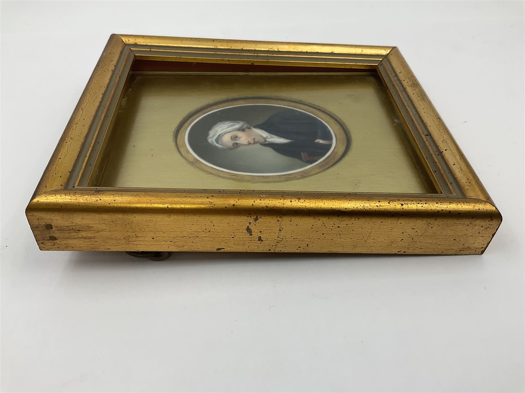 English School (18th century)
Portrait miniature upon ceramic plaque 
Head and shoulder portrait of a gentleman in blue coat and white turban, holding book under one arm
Indistinct inscription verso
Within gilt mount and gilt frame under glass
Portrait 7cm x 5.5cm 
Plaque 14cm x 11.5cm
Frame 16cm x 13.5cm