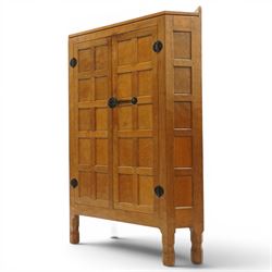 Mouseman - 1940's adzed and panelled oak corner cupboard, the raised quarter-gallery back over twin adzed panelled doors with wrought iron fittings and latch, enclosing three shaped shelves, raised on turned octagonal supports, with carved mouse signature in relief, by the workshop of Robert Thompson of Kilburn Provenance: purchased directly from the Kilburn workshop in the late 1940s