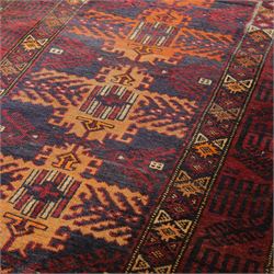 Baluch hand-knotted rug, deep red and indigo field decorated with a vertical arrangement of stylized geometric medallions within multiple narrow borders, 95x163cm, and Tekke Turkman rug, madder red field decorated with repeating rows of octagonal guls, framed by multiple geometric borders 84x129cm, (2)