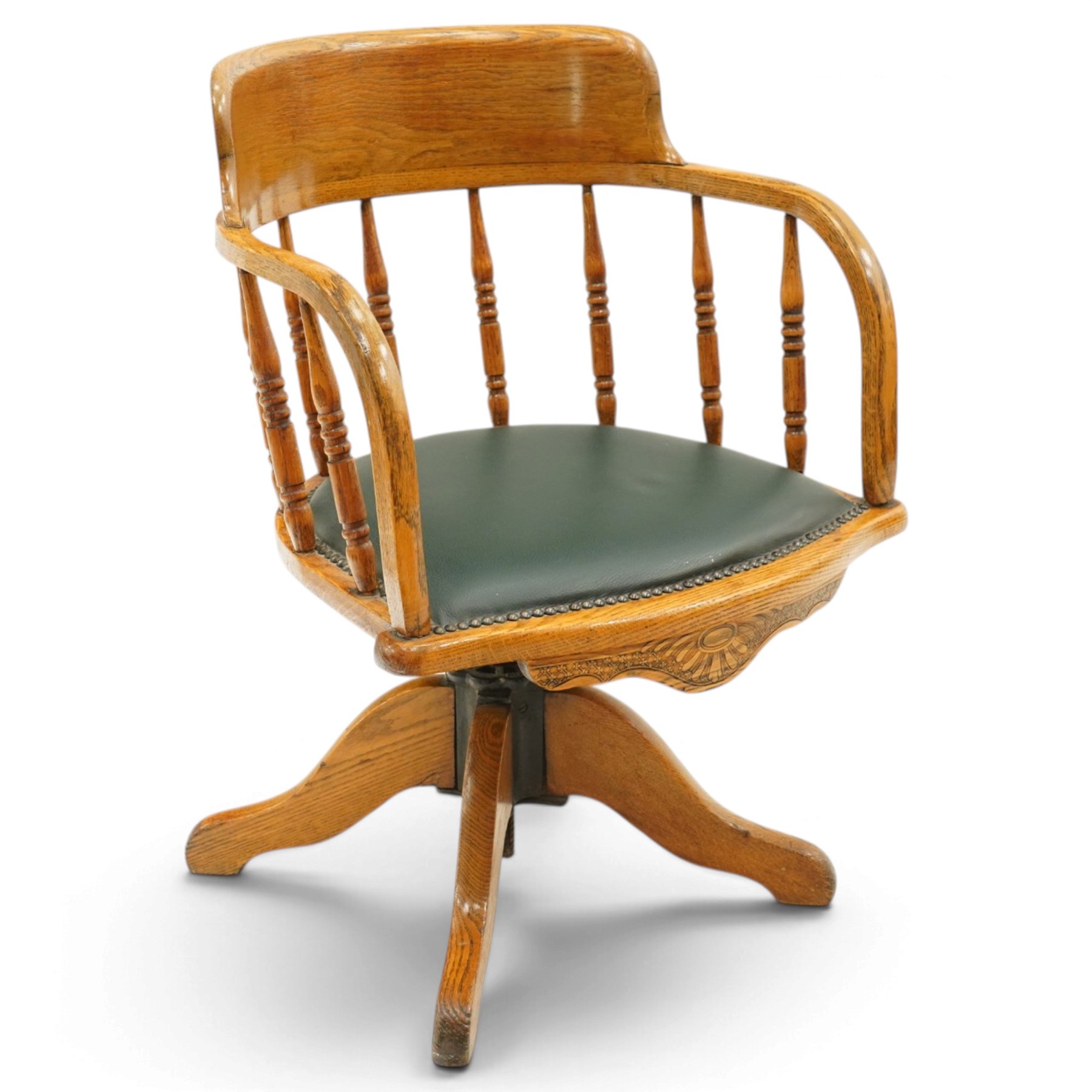 Edwardian oak captains swivel desk chair of tub form, shaped cresting rail over spindle supports and green-leather upholstered seat, foliate apron over swivel action and four-spoke base