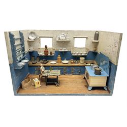 Late Victorian German white and blue painted pine diorama of a kitchen interior, the long work surface with inset wash bowl and cupboards under, various fitted shelves, tin-plate cooking range, wooden figure seated at a tin-plate table and well-stocked with various age ceramic, metal and wooden accessories L50cm H31.5cm D30cm