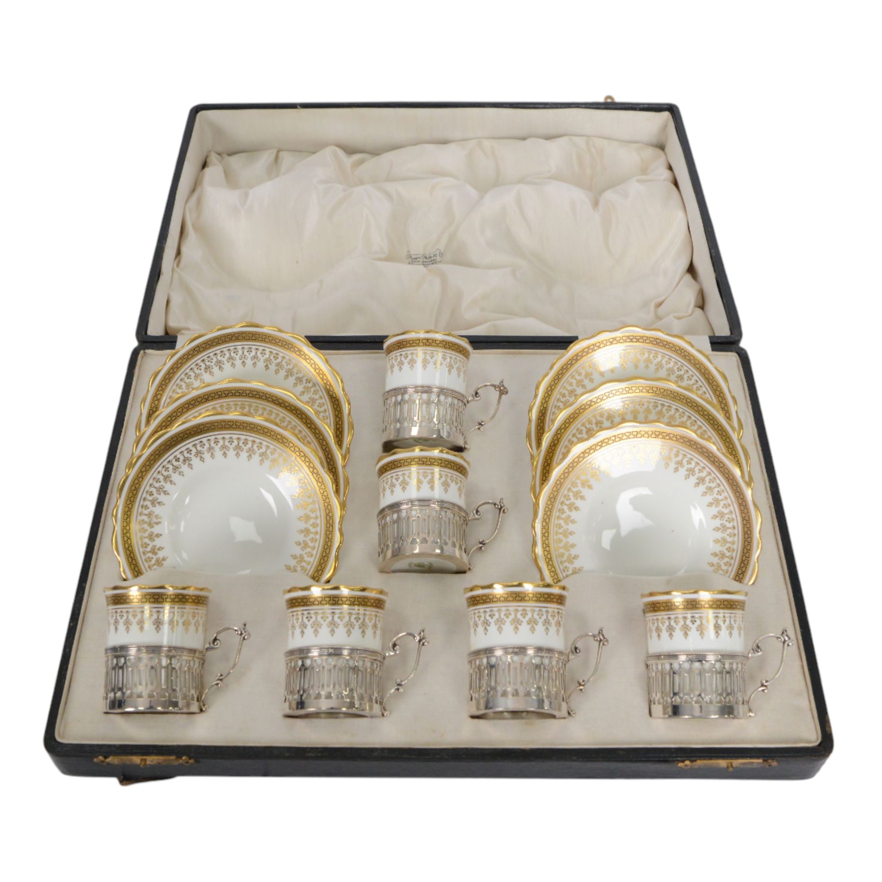 Boxed set of six Aynsley coffee cans and saucers, decorated with gilt greek key border, the cans within silver mounts, hallmarked Birmingham 1911