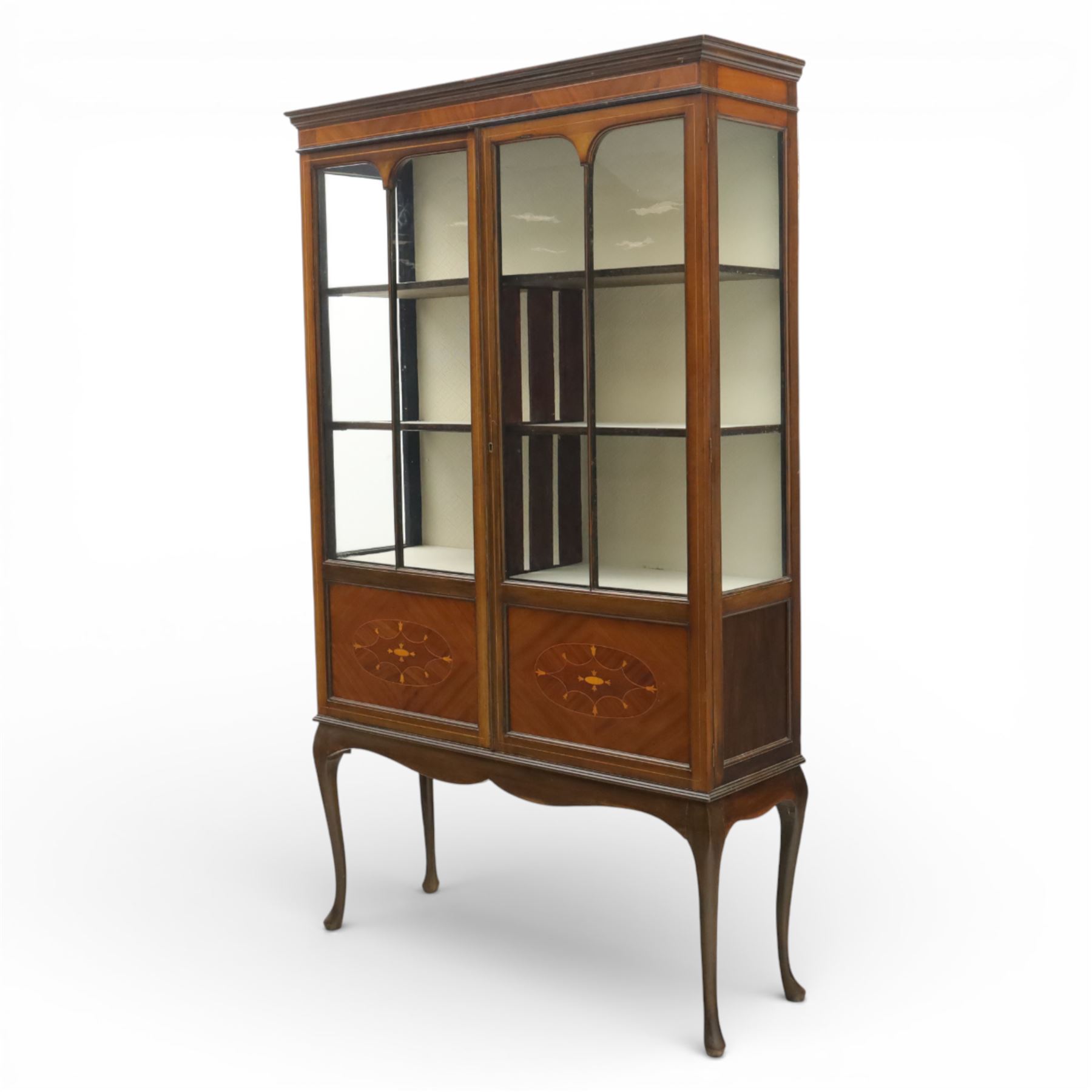 20th century Edwardian style mahogany display bookcase cabinet, the moulded cornice above two lancet glazed doors enclosing a shelved interior, the lower sections with oval inlaid fan decoration, supported on shaped cabriole legs