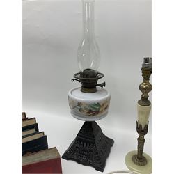 Oil lamp with ornate metal base and painted glass reservoir, together with two table lamps and books 