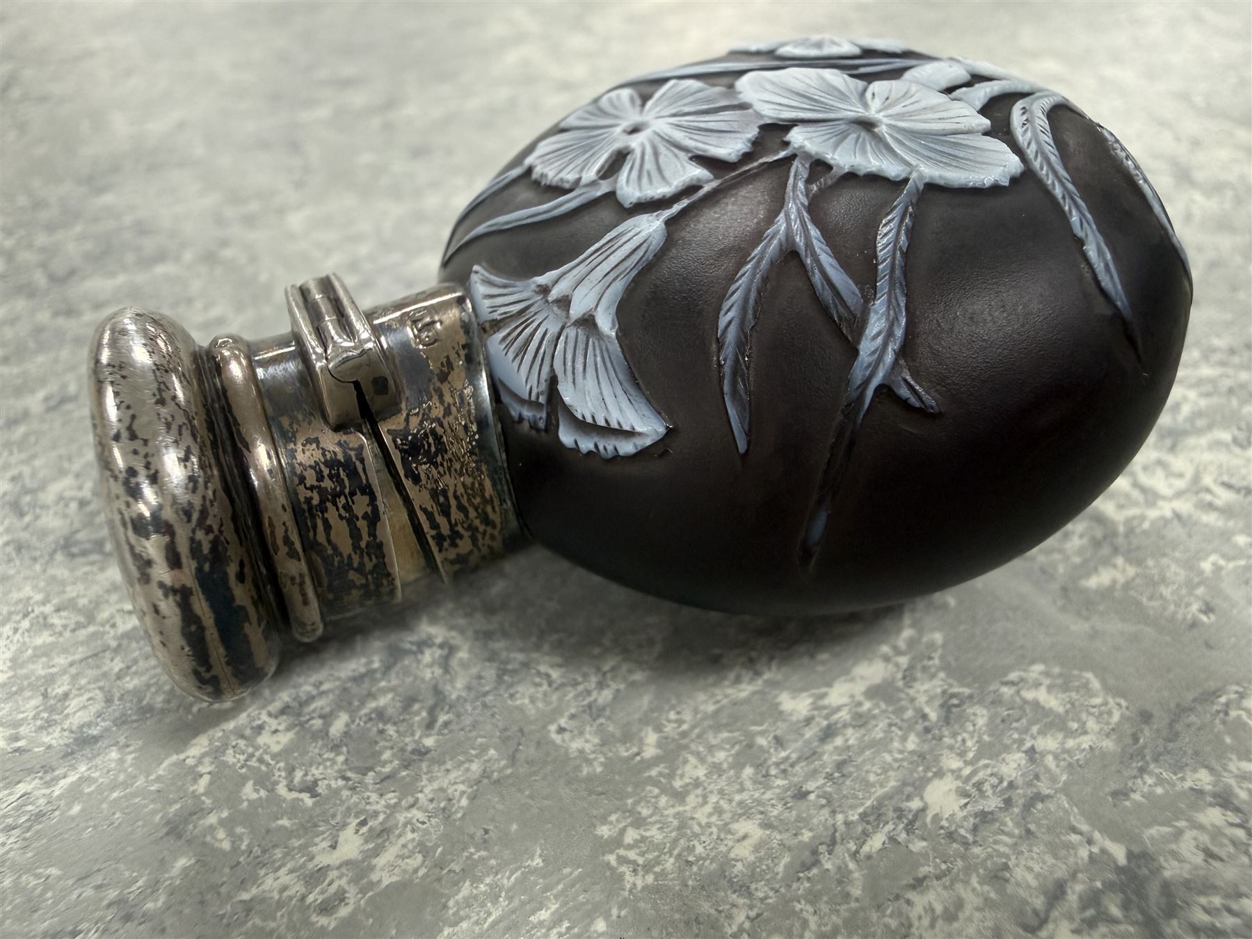 Victorian Thomas Webb silver mounted cameo glass scent bottle, hallmarked Sampson Mordan and Co, London 1884, the cameo glass body of circular form, decorated with white flowers and foliage in high relief upon a black ground, the hinged cover opening to reveal the original stopper, H6cm 