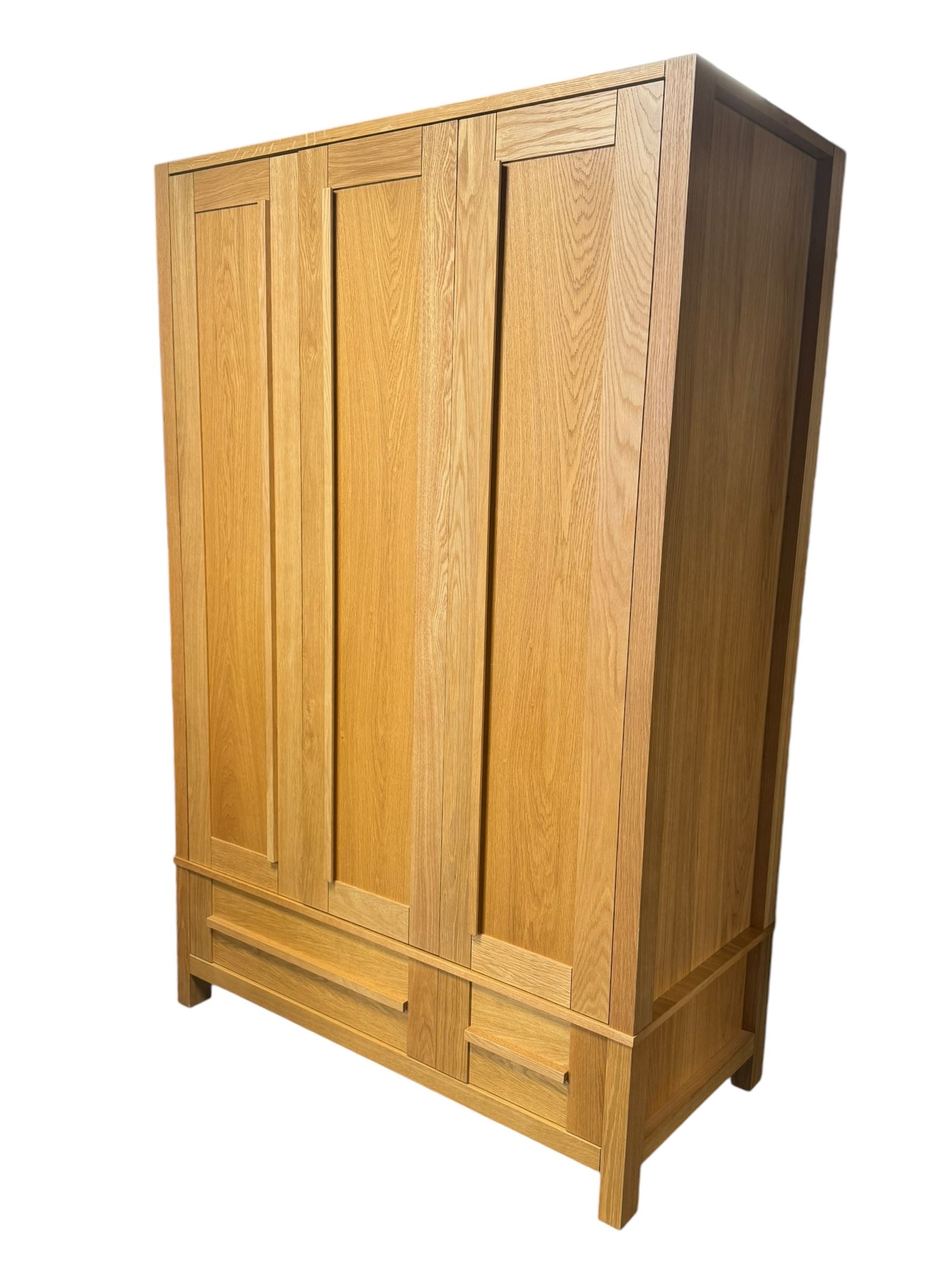 Contemporary light oak triple wardrobe, panelled doors with vertical linear design, left section enclosing hanging rail and single shelf, right section with adjustable shelves, over two drawers, on square stile supports