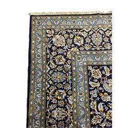 Central Persian Kashan indigo ground carpet, central lighter blue floral medallion surrounded by interlacing leafy branches and stylised plant motifs, the main border decorated with repeating floral motifs and scrolling branches, within guard stripes 