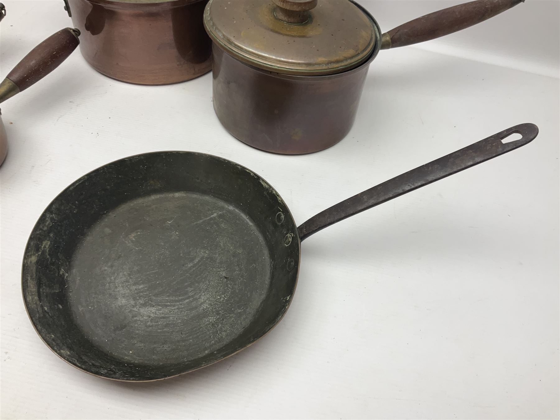 Four Victorian copper moulds, together with a graduating set of copper pans with wooden handles and finials to covers, largest pan 