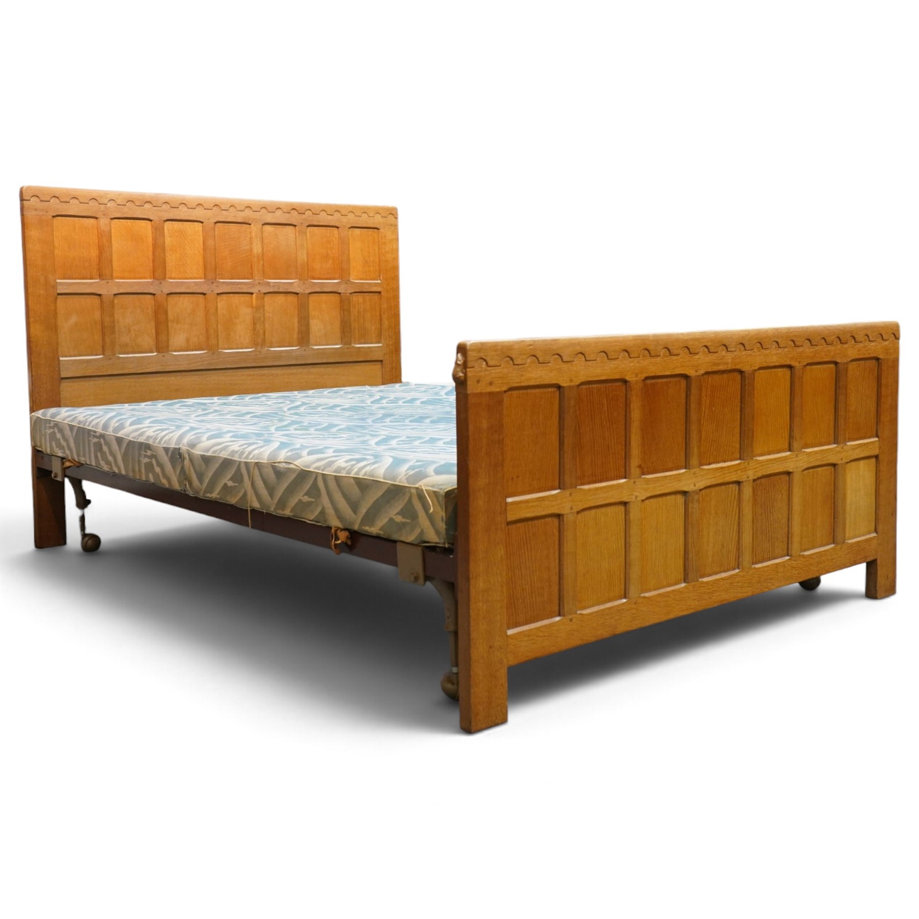 Mouseman - 4'6 panelled oak double bedstead, the head and footboard panelled with arcade carved cresting rails, with bed base and Vono metal rails, with carved mouse signature, by the workshop of Robert Thompson of Kilburn