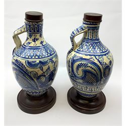 A pair of 20th century blue and white delft water jugs, the bodies decorated with stylised bands, and one example with a deer and the other with a hare, with later wooden spreading circular feet, and stoppers, overall H45cm. 