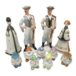 Group of eleven Aquincum of Budapest figures, comprising two of a man in a feather hat, seven dwarves, man and woman in traditional dress, all with printed marks beneath