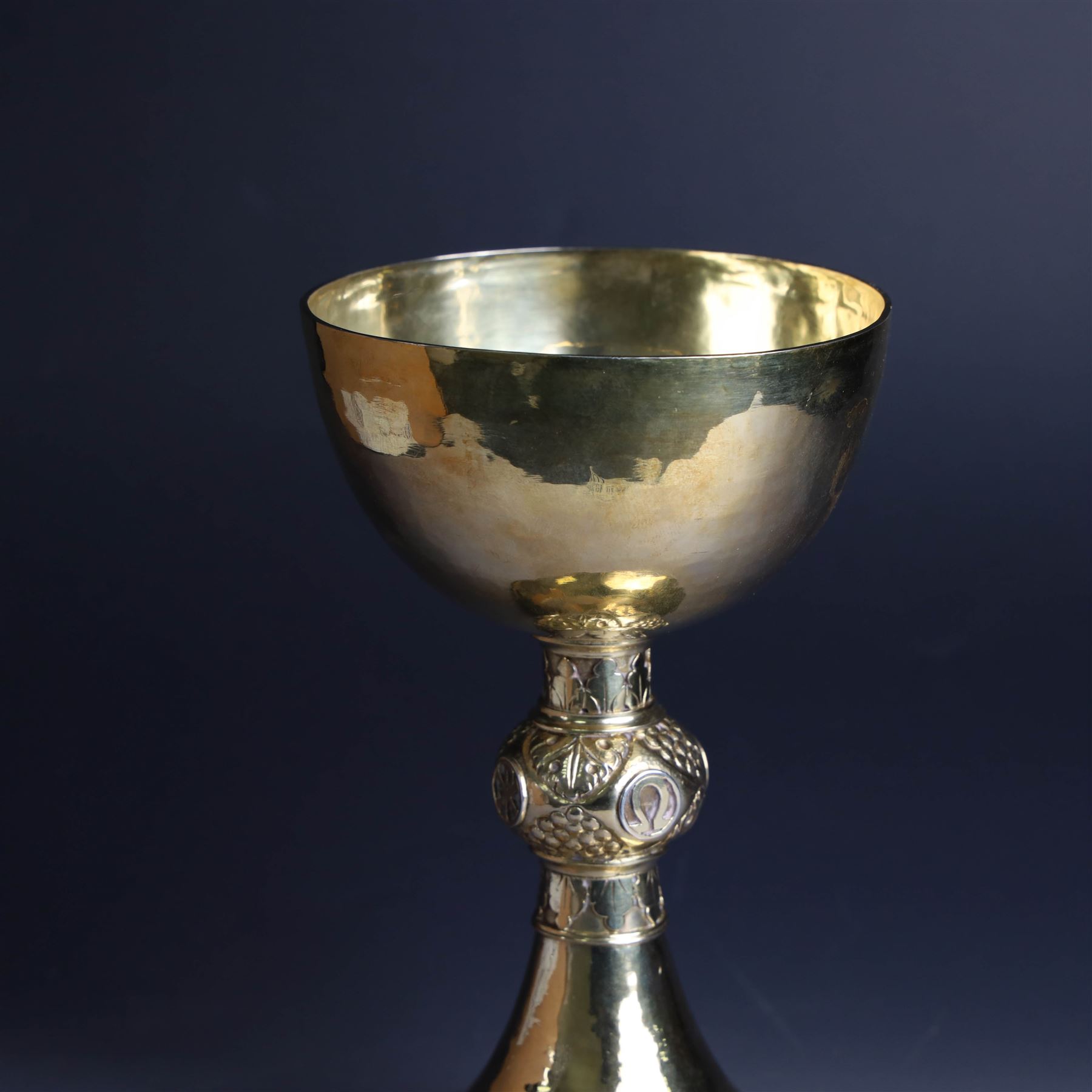Mid 20th century silver-gilt chalice, the goblet with hammered finish upon knopped stem, the knop embossed with symbols and foliate decoration, engraved to base ' veni non ministrari sed ministrare' and with presentation engraving to underside, hallmarked Guild of Handicraft, London 1957, H17cm
