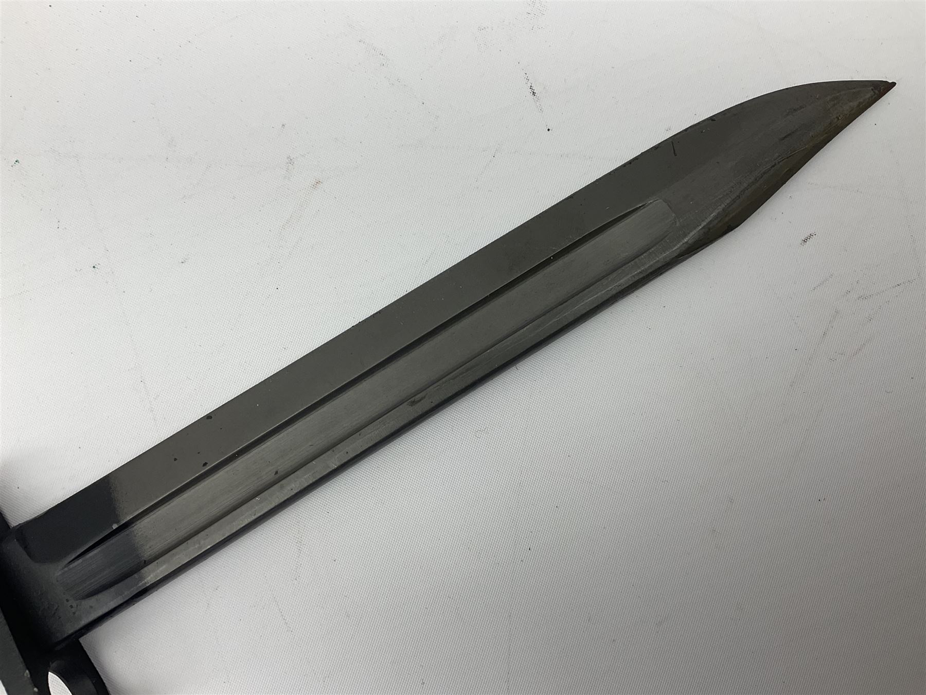 British Army L1A3 SLR Self Loading Rifle bayonet, with 20.5cm Bowie type fullered blade, hooked pommel with working push release button, grip secured by two deeply recessed rivets and marked L1A3 9600257 D71; in matching black scabbard L32.5cm overall