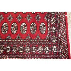 Two Afghan Bokhara crimson ground rugs, the fields decorated with repeating Gul motifs with geometric guard bands (126x190 & 157x250)